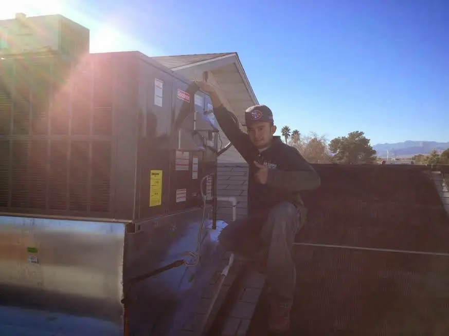 HVAC technician performing AC Tune-Up on a rooftop unit in Valley Falls